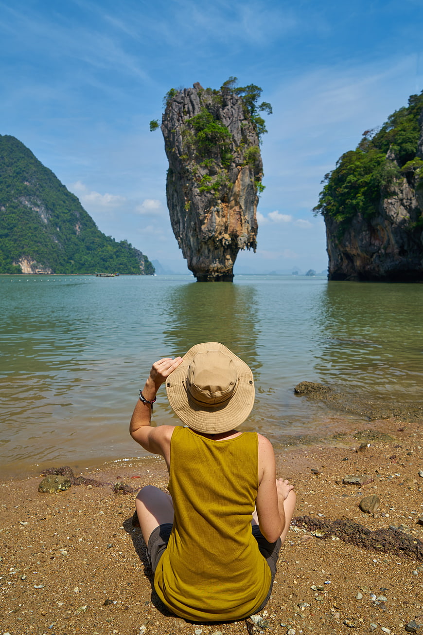 Woman sitting on tropical beach facing limestone karst island