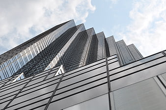 Low angle view of modern glass skyscraper architecture against cloudy sky