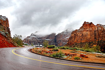 Winding Road Through Snowy Red Rock Canyon Under Dramatic Clouds