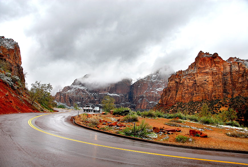 Winding Road Through Snowy Red Rock Canyon Under Dramatic Clouds