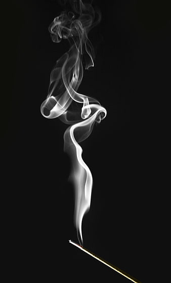 White incense smoke spiraling against black background