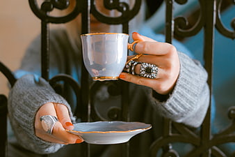 Woman holding vintage teacup with ornate rings
