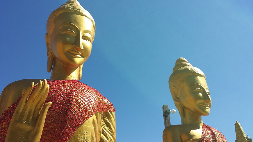 Golden Buddha Statues with Red Robes Against Blue Sky