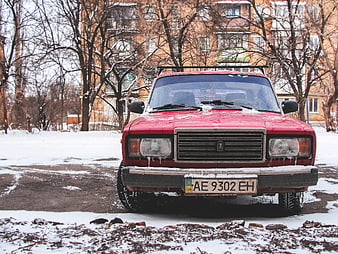 Front view of red vintage Lada car in winter snow