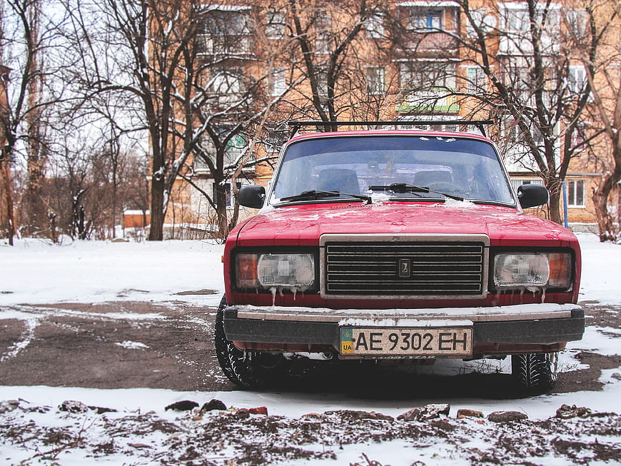 Front view of red vintage Lada car in winter snow