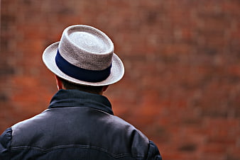 Man in Straw Fedora and Leather Jacket Against Red Brick Wall