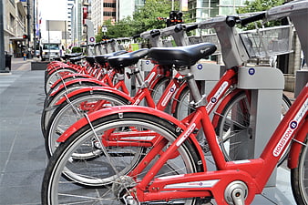 Row of red Houston Cycles public bicycles parked on a city street