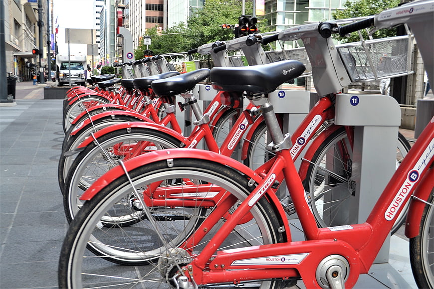 Row of red Houston Cycles public bicycles parked on a city street