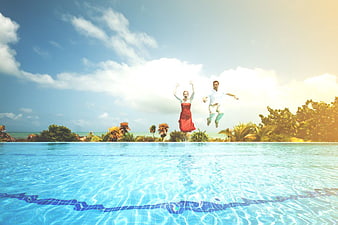 Happy Couple Jumping into Infinity Pool Tropical Vacation
