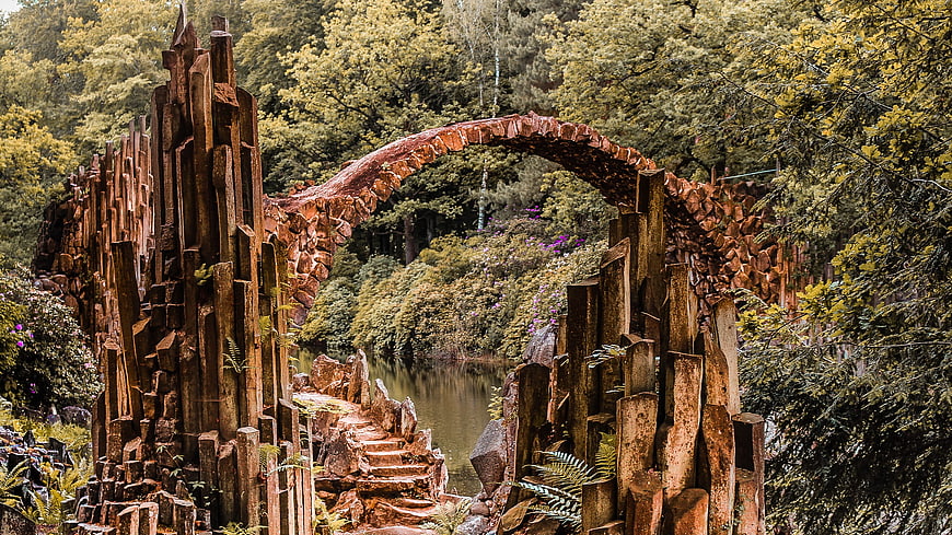 Historic Stone Arch Bridge Over Pond In Lush Forest