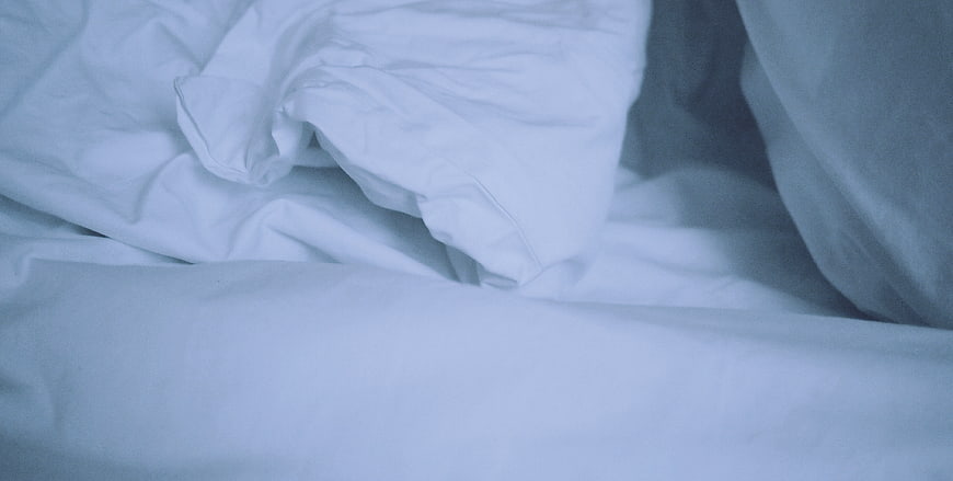 Close-up of rumpled white bed sheets and pillow