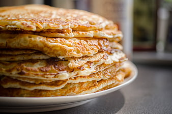 Stack of golden homemade pancakes on a white plate