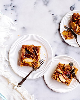 Overhead view of apple cake slices on white plates with forks