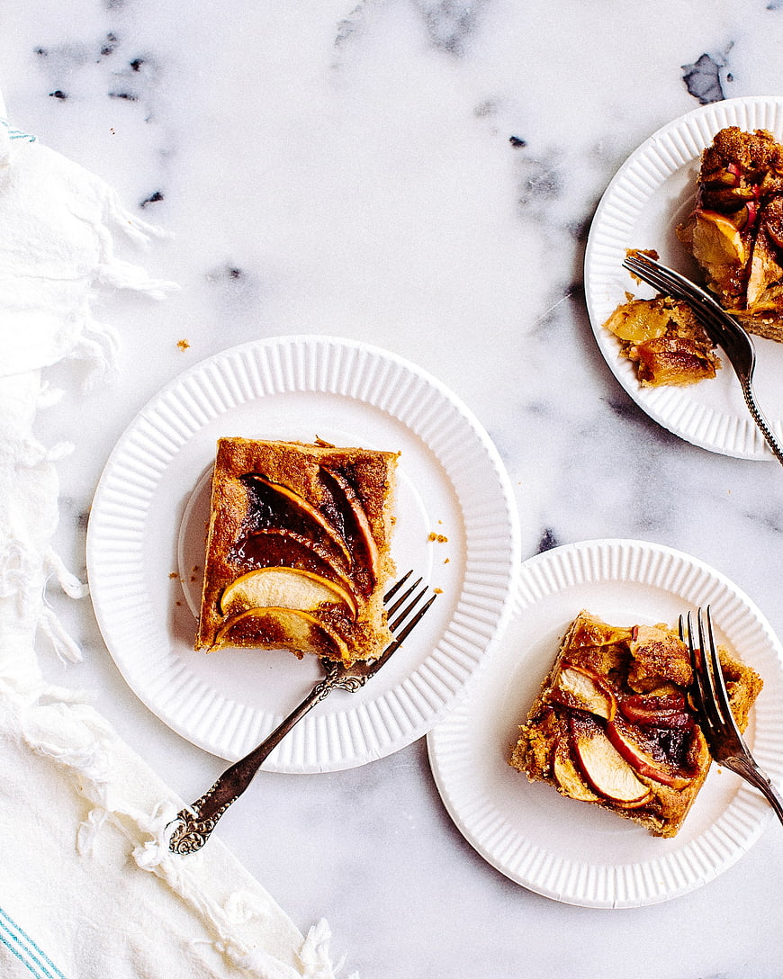 Overhead view of apple cake slices on white plates with forks