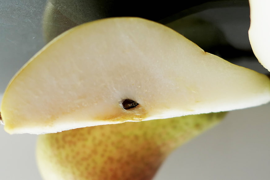 Close-up of a sliced pear with visible seed and textured skin