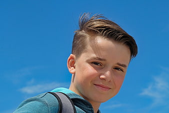 Portrait of smiling teenage boy against blue sky