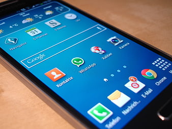 Close-up of smartphone screen with app icons on wooden table