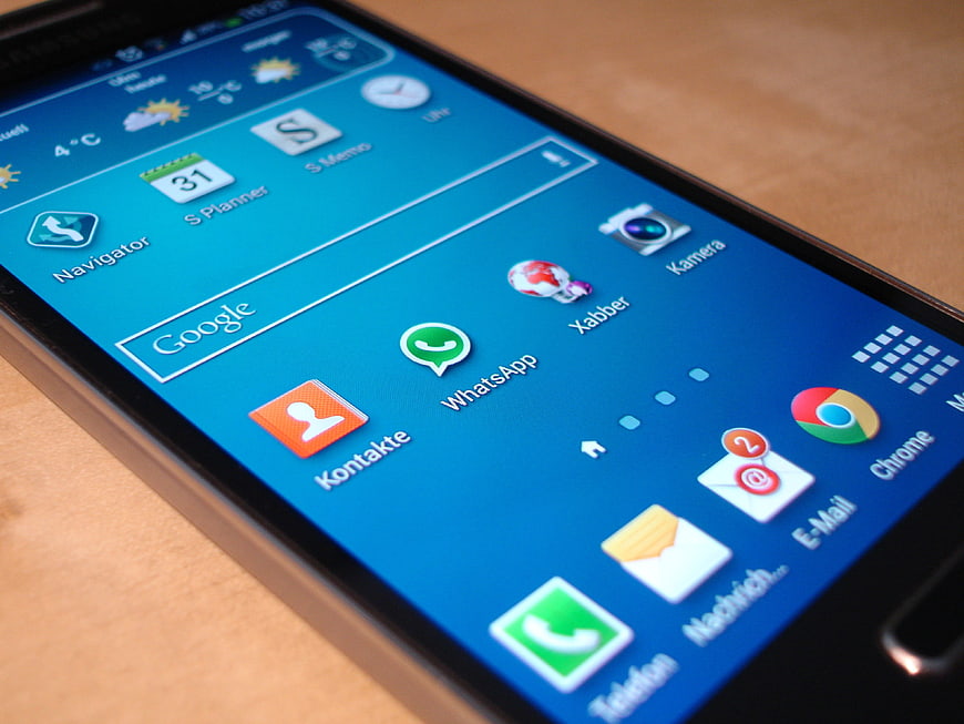 Close-up of smartphone screen with app icons on wooden table