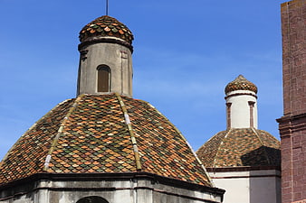 Colorful tiled domes of a historic church in Bosa, Sardinia