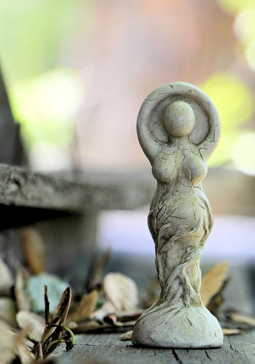Ancient Stone Goddess Sculpture on Wooden Surface