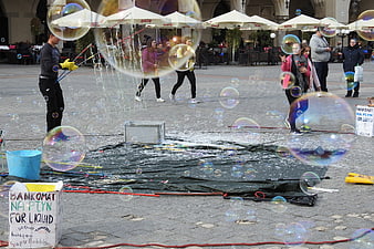 Street performer creating giant soap bubbles in a public square