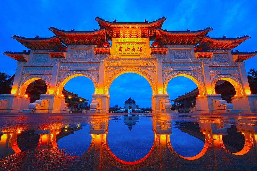 Traditional Chinese Archway Illuminated at Dusk with Water Reflection