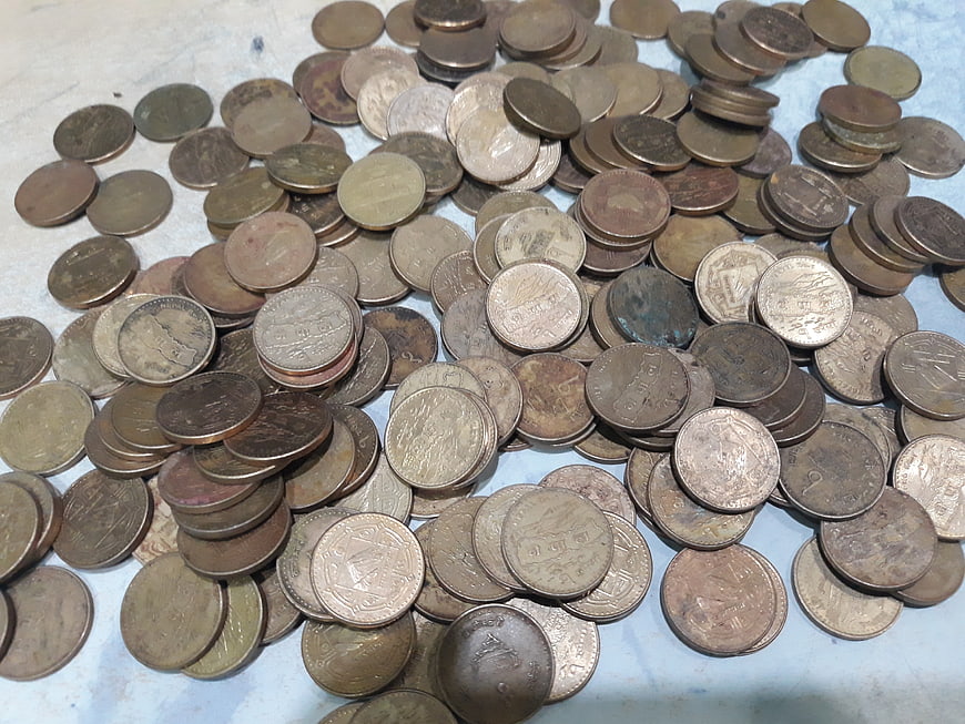 Pile of old Nepali coins on a light blue surface