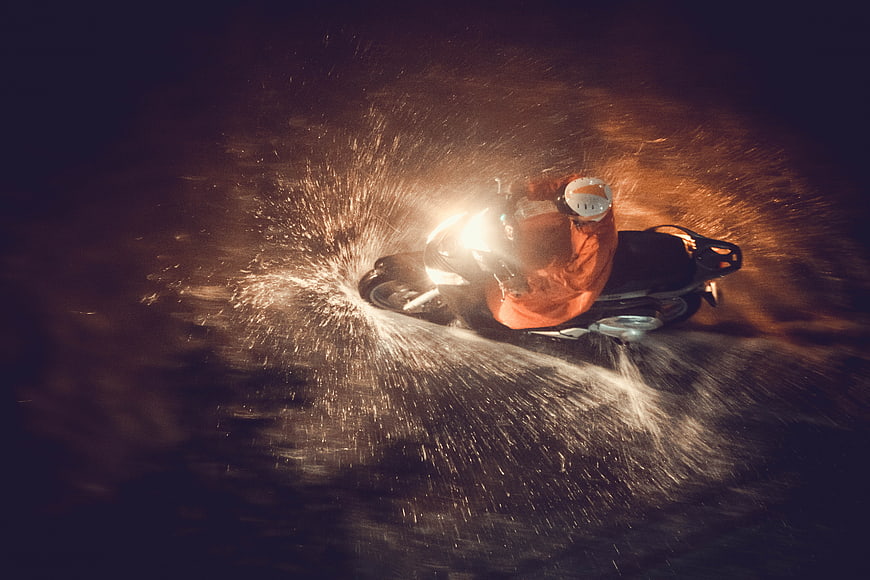 Motorcyclist riding through deep water at night with headlight