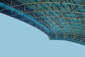 Blue stadium roof truss structure against clear sky