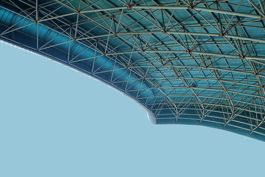 Blue stadium roof truss structure against clear sky
