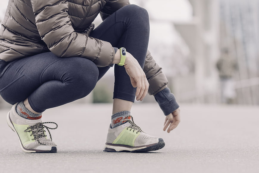 Female runner tying shoelaces on city street