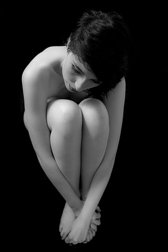 Black and white portrait of a woman in a curled up fetal position