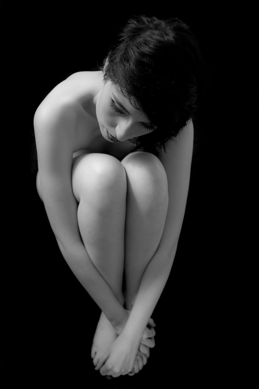 Black and white portrait of a woman in a curled up fetal position