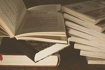Vintage open book resting on a stack of classic literature