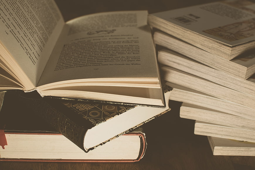 Vintage open book resting on a stack of classic literature