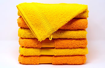 Stack of Yellow and Orange Bath Towels on White Background