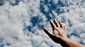 Hand Reaching Up to Blue Sky with Clouds