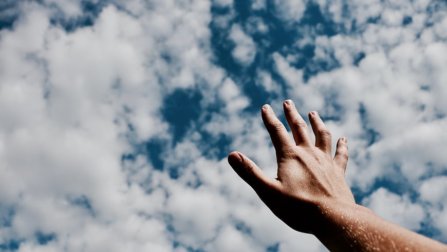 Hand Reaching Up to Blue Sky with Clouds
