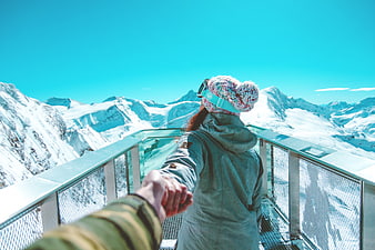 Couple holding hands on snowy mountain viewing platform