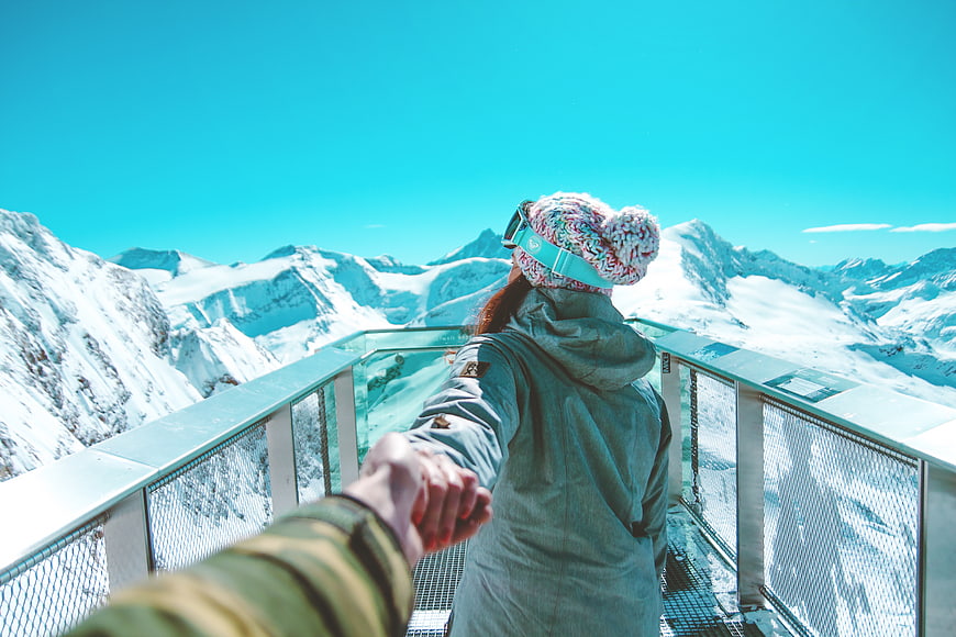 Couple holding hands on snowy mountain viewing platform
