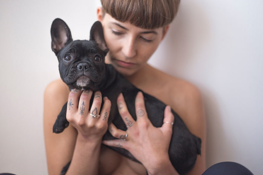 Woman with tattoos holding black French Bulldog puppy
