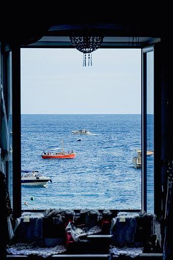 View of blue sea and boats through a window frame