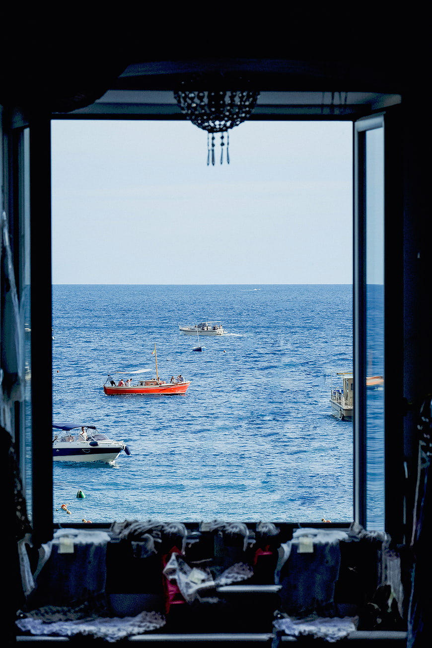 View of blue sea and boats through a window frame