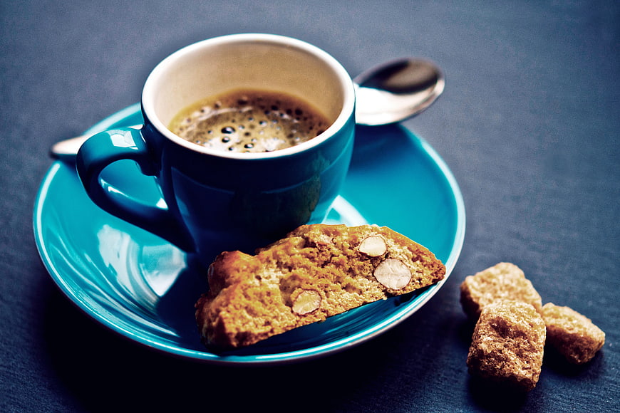 Blue Coffee Cup with Biscotti and Brown Sugar on Dark Table