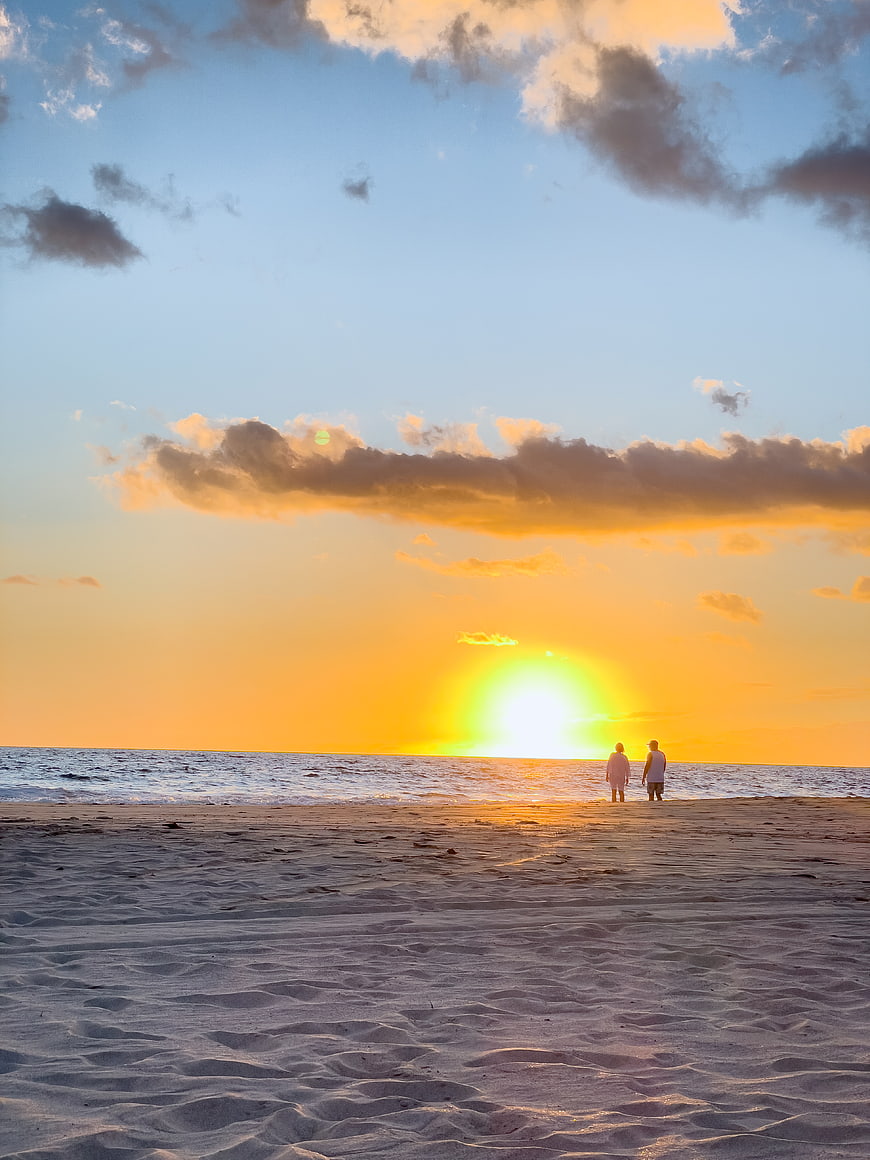 Couple Walking on Sandy Beach at Golden Sunset