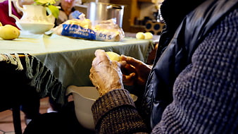 Senior woman peeling boiled eggs at a communal table