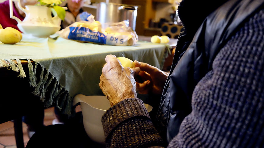 Senior woman peeling boiled eggs at a communal table