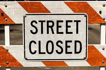 Street Closed Sign on Orange and White Barrier