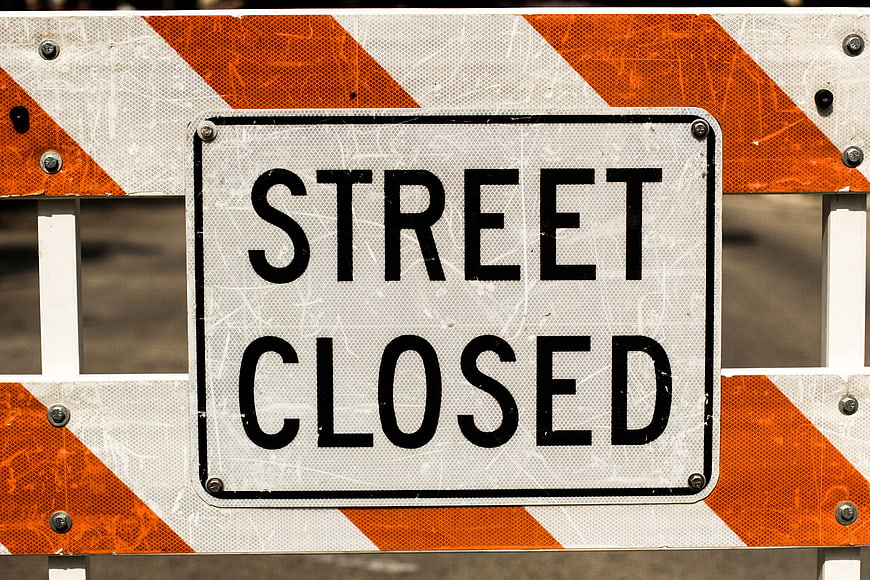 Street Closed Sign on Orange and White Barrier