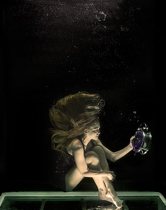 Underwater Portrait of Woman Holding Clock in Dark Water